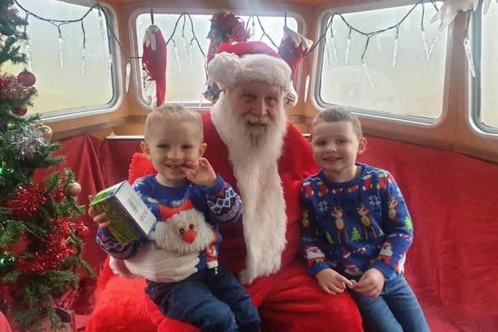 Santa with two children in Christmas sweaters on a festive boat.