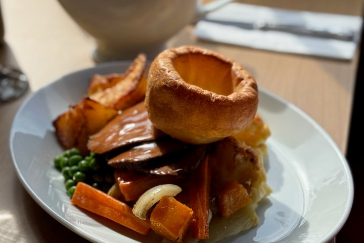 Plate with roast meat, Yorkshire pudding, vegetables, and gravy boat.