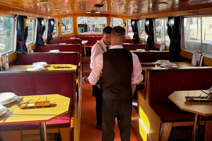 Two servers in a wooden-decor dining boat with red booths.