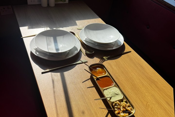 Dining table with plates and condiments under sunlight.