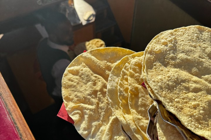 Yellow corn tortillas held above stairs with a person in the background.